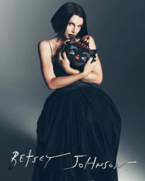 Julia Fox in a black gown holding a novelty cat handbag for Betsey Johnson Holiday 2026