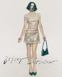 Julia Fox in a floral slip dress holding a black handbag against a white background for the Betsey Johnson Holiday 2026 campaign