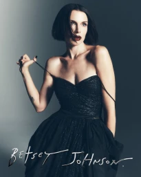Julia Fox wearing a sparkling black strapless dress against a grey studio backdrop for Betsey Johnson Holiday 2026 Campaign