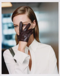 Model wearing a white shirt with a leather glove held over her face for the Kith Women Autumn 2026 campaign.
