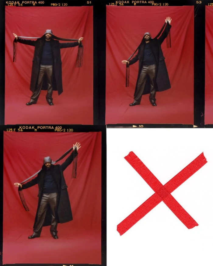 Chiwetel Ejiofor in a black coat holding long fringed scarves against a red backdrop for Esquire UK