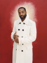 Chiwetel Ejiofor wearing a heavy white double-breasted coat against a textured red background with a glowing white halo effect.