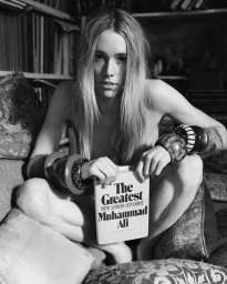 Black and white portrait of a woman seated holding a book by Muhammad Ali wearing large bracelets