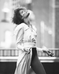 Black and white portrait of a woman in a white coat with her head tilted back outdoors for System Magazine.