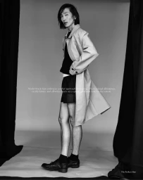 Model Hyuk Kim in a beige trench coat and black shorts posing in a studio for The Perfect Man Magazine