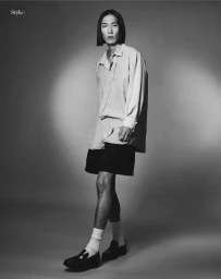 Model Hyuk Kim in striped shirt and dark shorts posing against a grey studio backdrop for The Perfect Man Magazine.