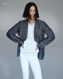 Model Hyuk Kim wearing grey blazer and white sweater smiling in editorial by Ferran Casanova for The Perfect Man Magazine.