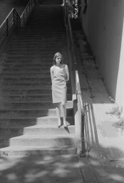 Woman in simple dress standing on outdoor concrete steps with strong shadows for Another Way editorial