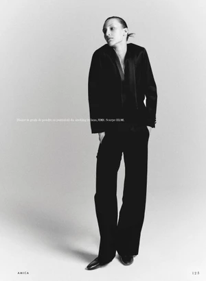 Model in black suit standing against a plain background for Amica Film Rosso editorial
