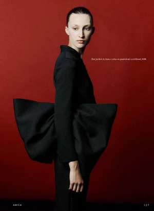 Model Andrea Östlund in a black sculptural jacket against a bold red background for Amica project Film Rosso