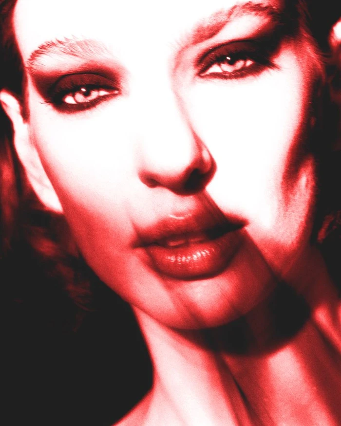 Close-up portrait of a woman with dramatic red and black high-contrast lighting and heavy eye makeup for Flanelle Magazine