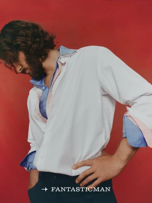 Andrew Garfield posing in a white button-down shirt against a bold red background for Fantastic Man China.