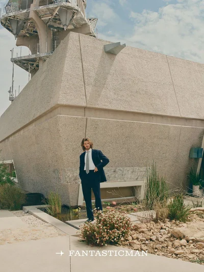 Actor Andrew Garfield in a dark suit standing before a brutalist concrete building for Fantastic Man China