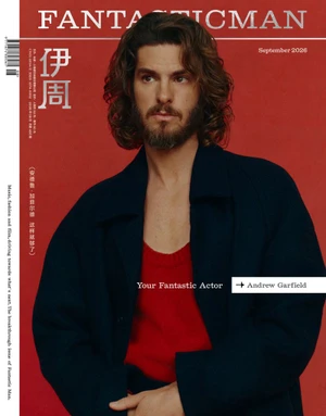 Andrew Garfield with long hair and beard wearing a red top and dark coat against a red backdrop for Fantastic Man China.