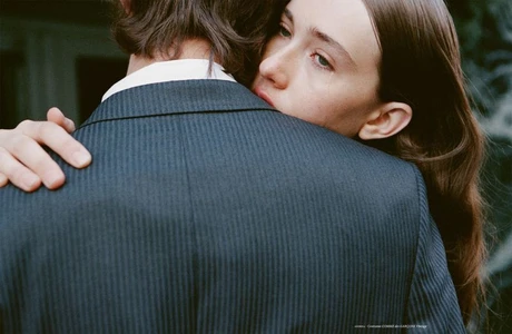 Close-up portrait of a woman embracing a person in a dark pinstripe suit, photographed by Linus Morales for Coeur Magazine.