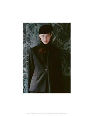 Model wearing a black blazer and beret standing against a dark marble wall in an editorial portrait for Coeur Magazine.