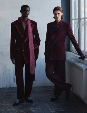 Two male models in matching burgundy velvet suits standing in a room with a window and radiator for V Man fall fashion.