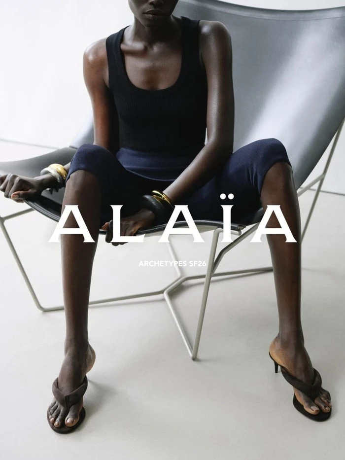 Athiec Geng seated in a leather sling chair wearing a black tank top and dark trousers for Alaïa