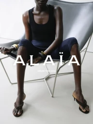 Athiec Geng seated in a leather sling chair wearing a black tank top and dark trousers for Alaïa
