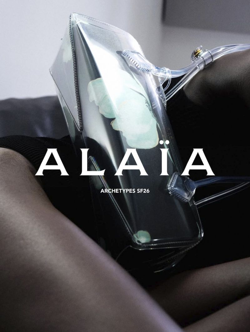 Close-up of a clear transparent designer handbag held against a dark background in an Alaia fashion campaign.