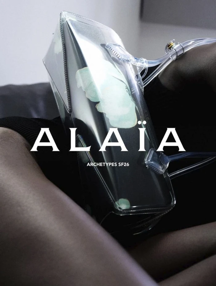Close-up of a clear transparent designer handbag held against a dark background in an Alaia fashion campaign.