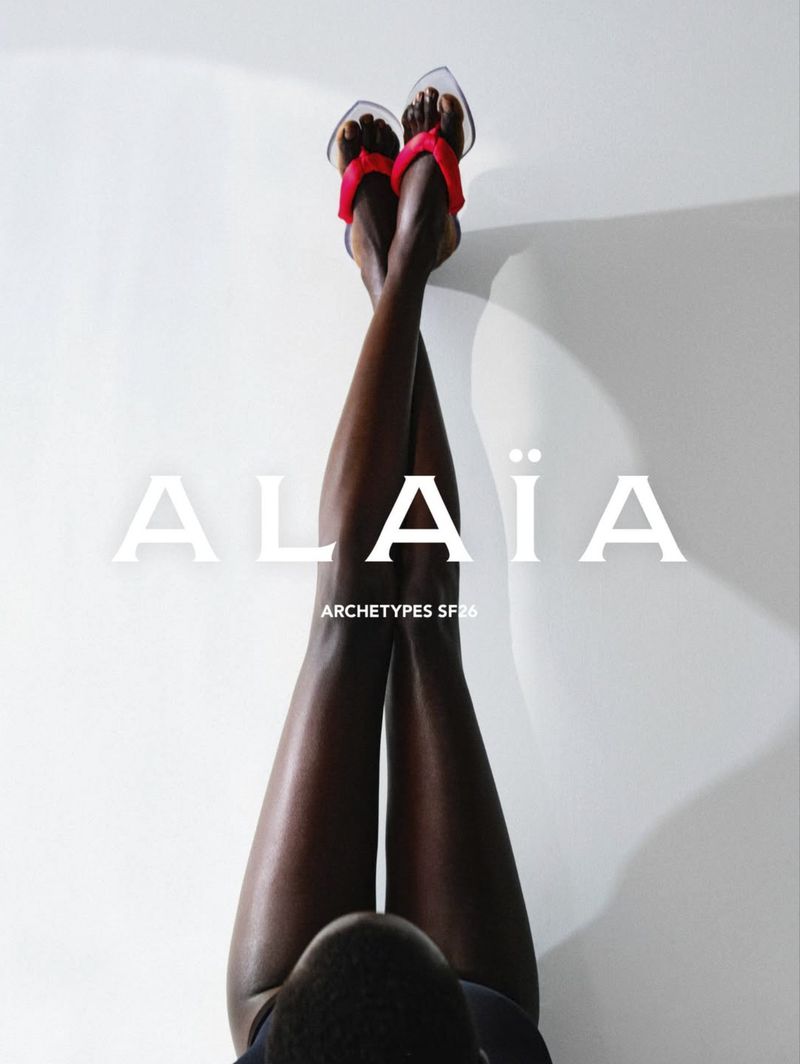 Model with crossed legs wearing heeled sandals against a plain background for Alaia