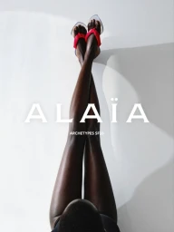 Model with crossed legs wearing heeled sandals against a plain background for Alaia