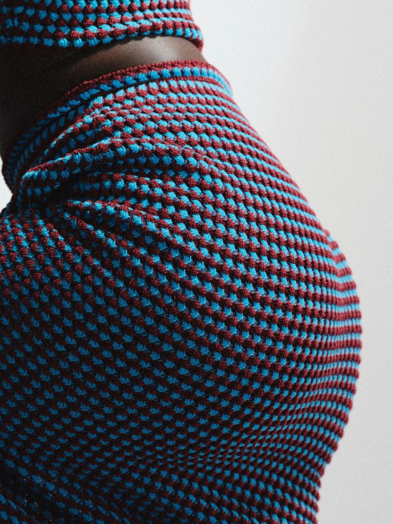 Close-up of a model wearing a textured knitted two-piece outfit in blue and burgundy against a plain light background.
