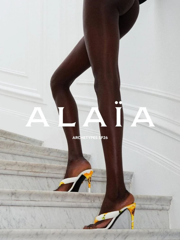Model walking up white marble stairs wearing heeled mules in the Alaia Archetypes SF26 campaign.