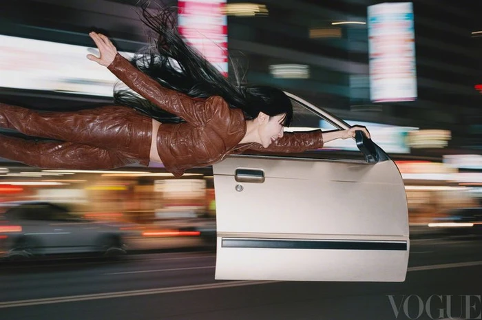 Michelle Yeoh flying horizontally alongside a car door against a blurred city street at night for Vogue China