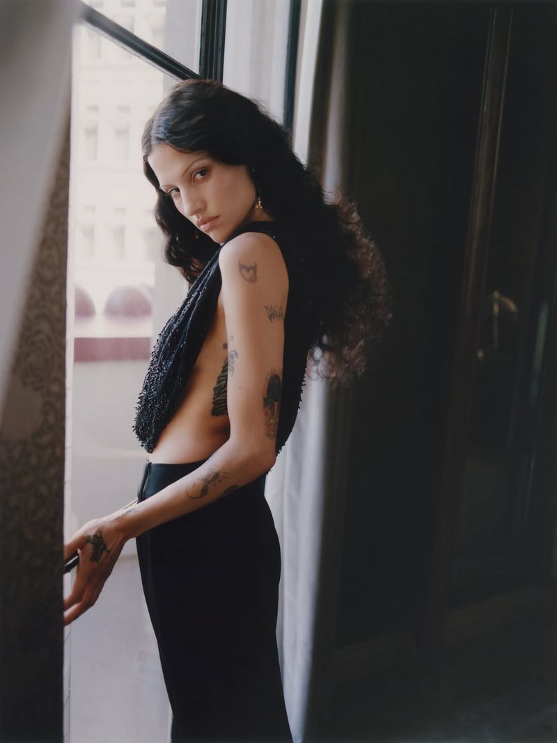Gabbriette in dark clothing standing near a bright window for Vogue Mexico photographed by Pía Riverola