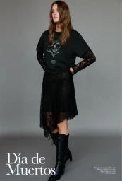 Model in black t-shirt over lace sleeves, black skirt, and laced boots against a grey seamless background