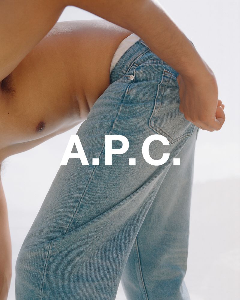 Fashion shot featuring a shirtless adult male model wearing light blue denim jeans in a bright indoor setting, showcasing the A.P.C. brand.