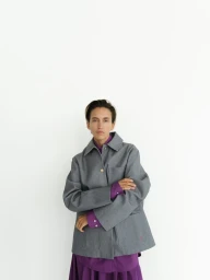 Model wearing a grey jacket over a purple shirt against a white backdrop for Rika Studios lookbook