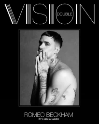Black and white portrait of Romeo Beckham posing with tattooed hands covering the lower part of his face.