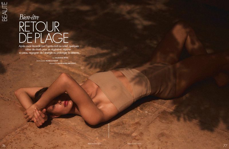 Tan-toned fashion editorial featuring a woman lying on a stone surface with shadows creating dappled light, promoting skincare and beauty.