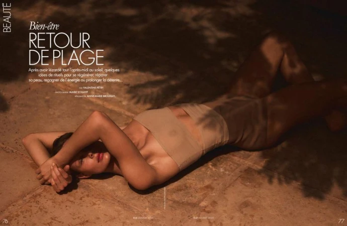 Tan-toned fashion editorial featuring a woman lying on a stone surface with shadows creating dappled light, promoting skincare and beauty.