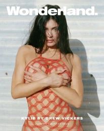 Kylie Jenner wearing an orange mesh dress against a corrugated metal wall photographed by Drew Vickers