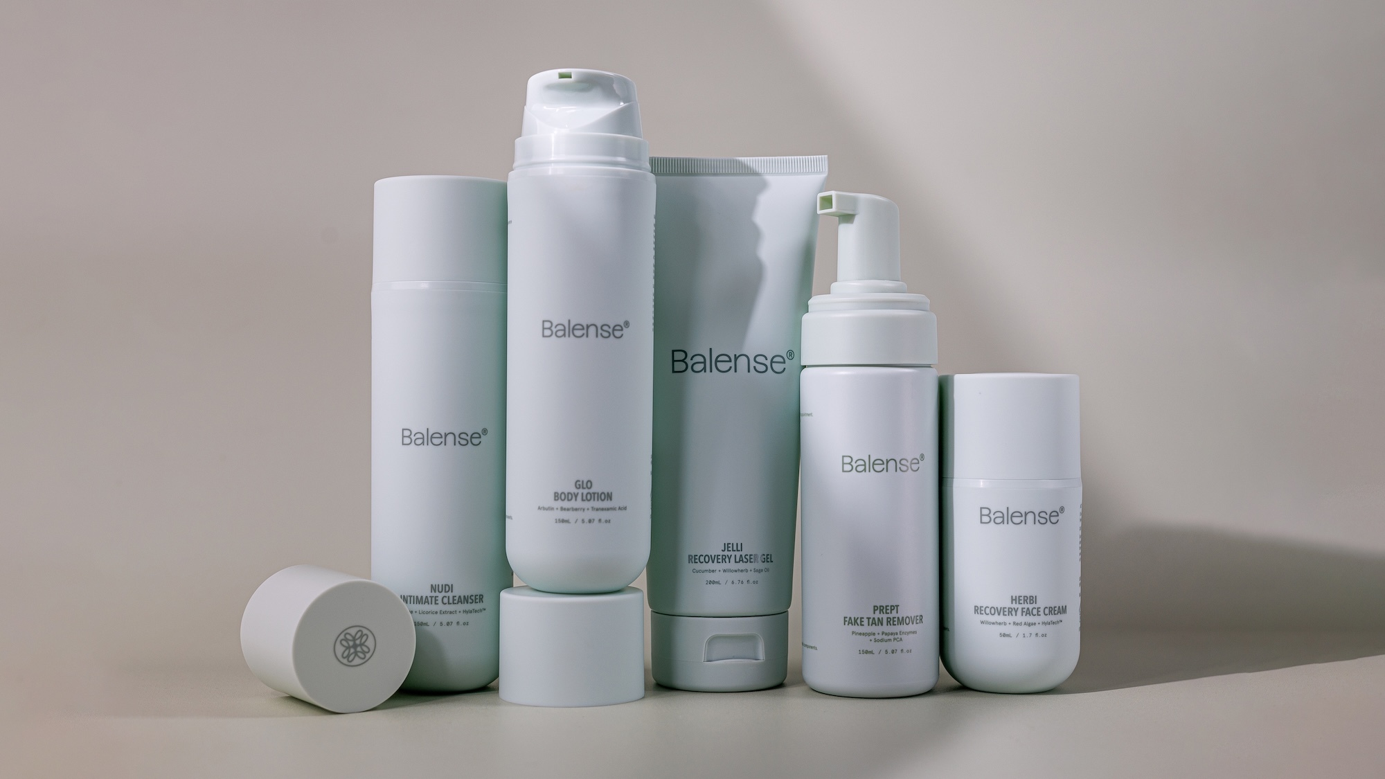 A collection of five white skincare product bottles and tubes with Balense branding arranged on a neutral grey background.