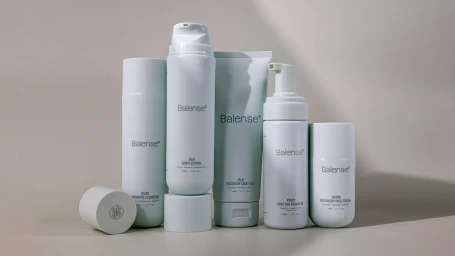 A collection of five white skincare product bottles and tubes with Balense branding arranged on a neutral grey background.
