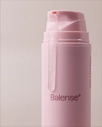 Pink Balense skincare pump bottle with a clear serum dripping down the dispenser against a neutral background