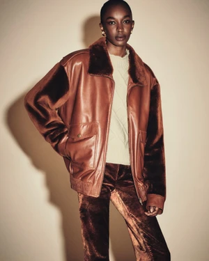 Model wearing a brown leather jacket and velvet trousers against a neutral background for FRAME Pre-Spring 27.