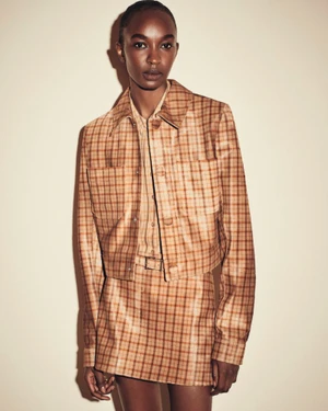 Model wearing a brown plaid jacket and matching mini skirt against a neutral background for FRAME.