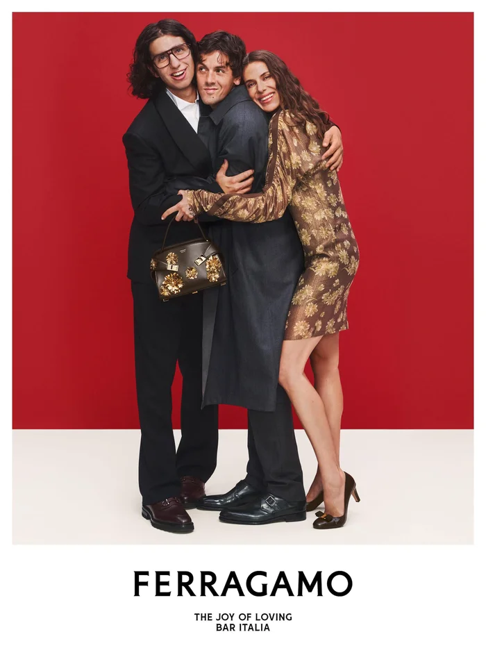Three people embracing tightly against a red and cream studio background for Ferragamo campaign