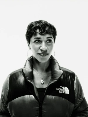 Portrait of a woman with short dark hair wearing a black puffer jacket against a seamless white background for The North Face.