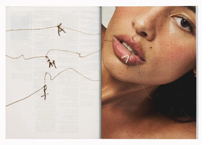 Close-up of a woman biting a delicate pave diamond letter pendant necklace for Mejuri