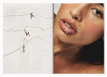 Close-up of a woman biting a delicate pave diamond letter pendant necklace for Mejuri