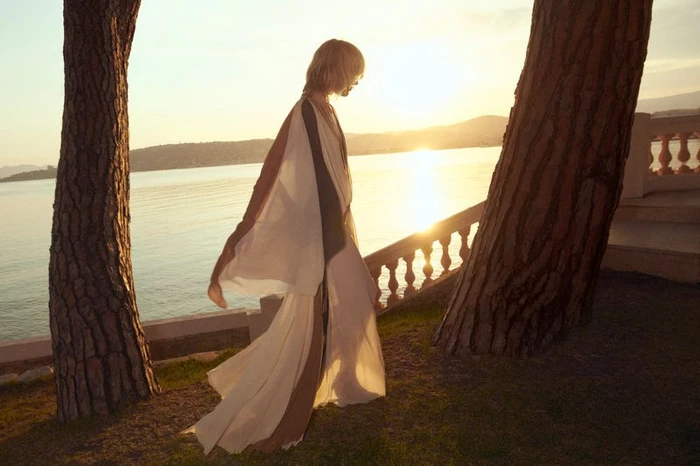 Model Aivita Muze walking along a coastal terrace at sunset in a flowing white and brown Zimmermann dress.