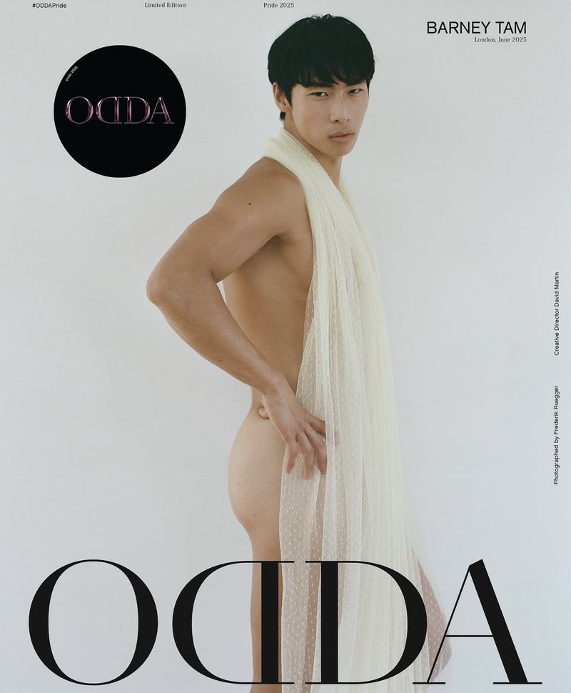 Fashion editorial featuring a shirtless Asian man wrapped in a sheer, textured fabric on a clean white backdrop, studio lighting.