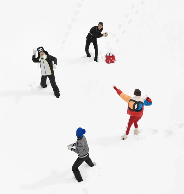 Aerial view of four models in winter ski apparel throwing snowballs on a snowy field for Chanel Coco Neige 2026